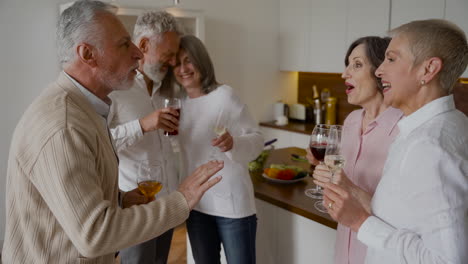 Gruppe-Fröhlicher-älterer-Freunde,-Die-In-Der-Küche-Lachen-Und-Wein-Trinken