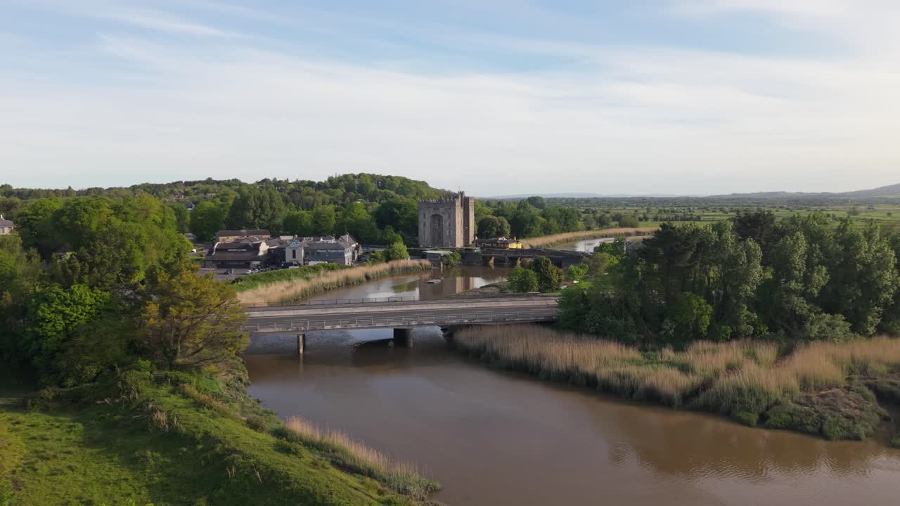 Bunratty castle and surrounding village by a calm river in county clare, aerial view