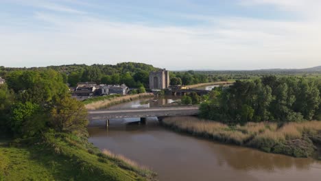 bunratty castle and surrounding village by a calm river in county clare, aerial view