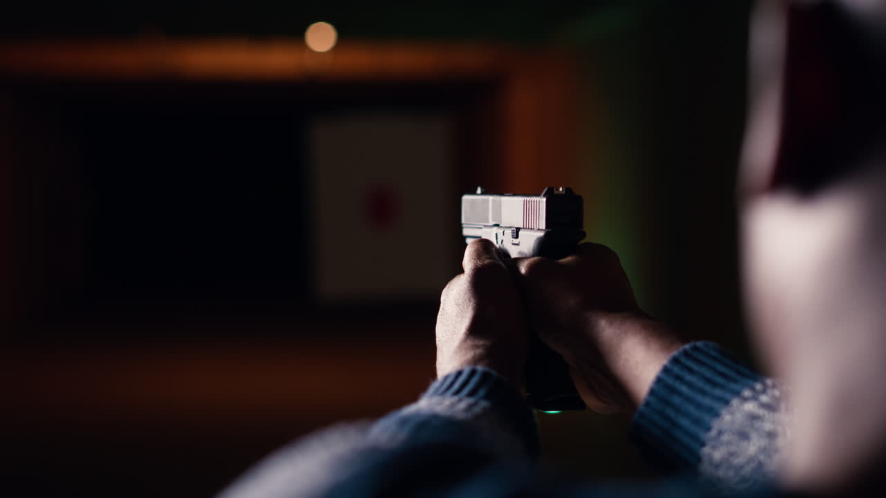 hombre en la galería de tiro usando un arma, mirando los resultados en el objetivo en movimiento, primer plano