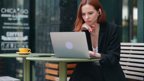 mujer trabajando en una computadora portátil en un café al aire libre