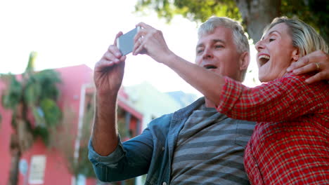 Feliz-Pareja-Sentada-En-Un-Banco-Tomando-Un-Selfie