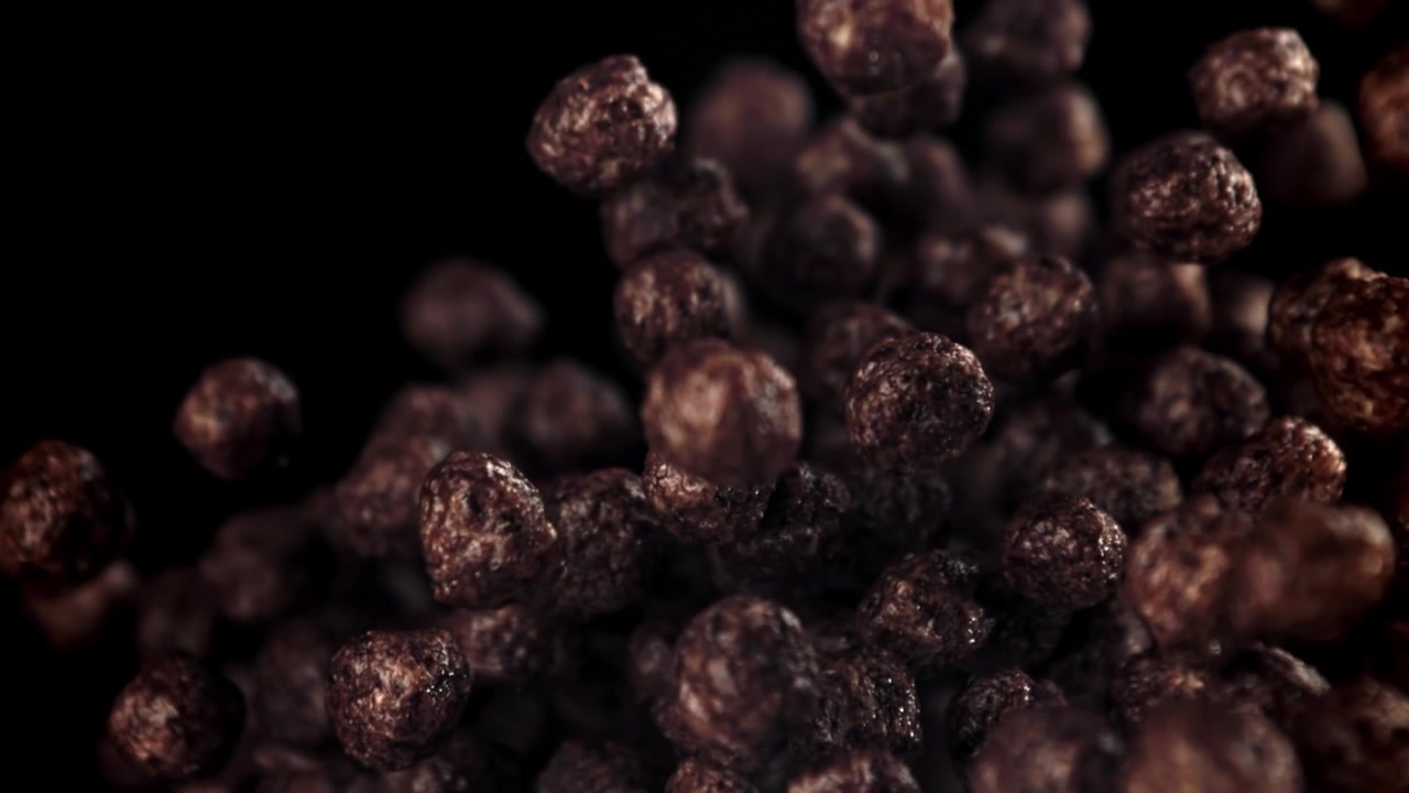 Palline di cereali al cioccolato che cadono al rallentatore su sfondo nero
