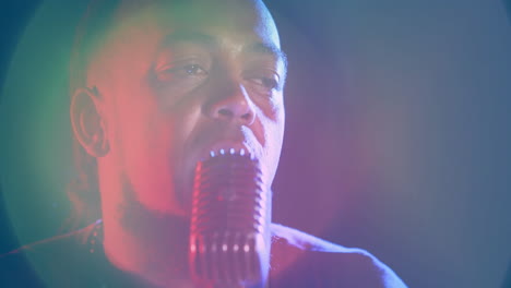 male singer performing into retro mic under red green spotlights showing music design