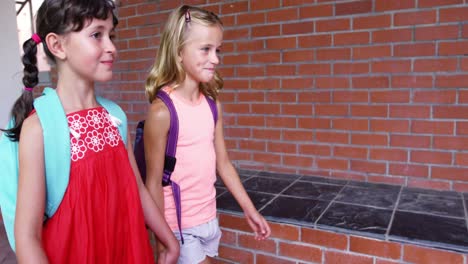 School-girl-holding-hands-and-walking-together-in-corridor-at-school