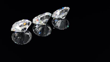 close up of three oval brilliant cut diamonds sparkling and rotating on black background