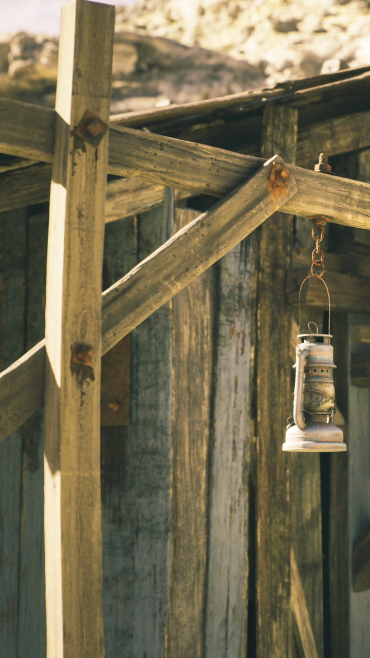 Lantern hangs gently in the warm glow of sunlight near a rustic cabin