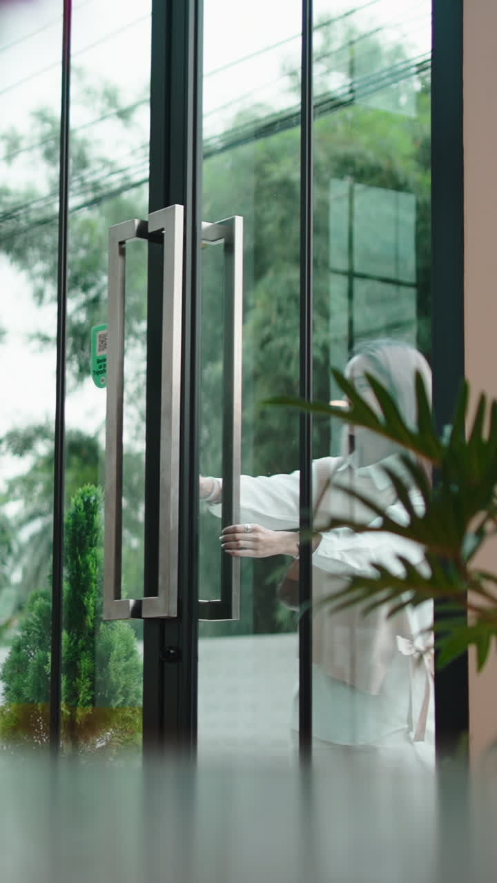 Uma mulher sorridente abre uma porta de vidro