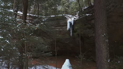 ash cave with icicles hanged on the cliff and ice cone in hocking hills state park, south bloomingville, ohio