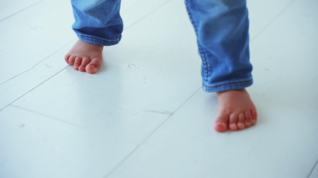 Toddler's Bare Feet Taking First Steps on White Floor