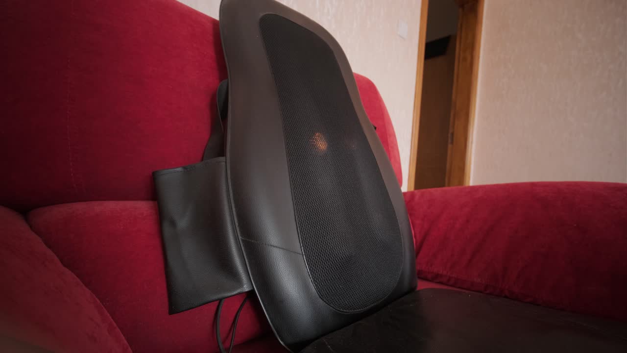 Almofada de Massagem Elétrica Funcionando em uma Poltrona Vermelha