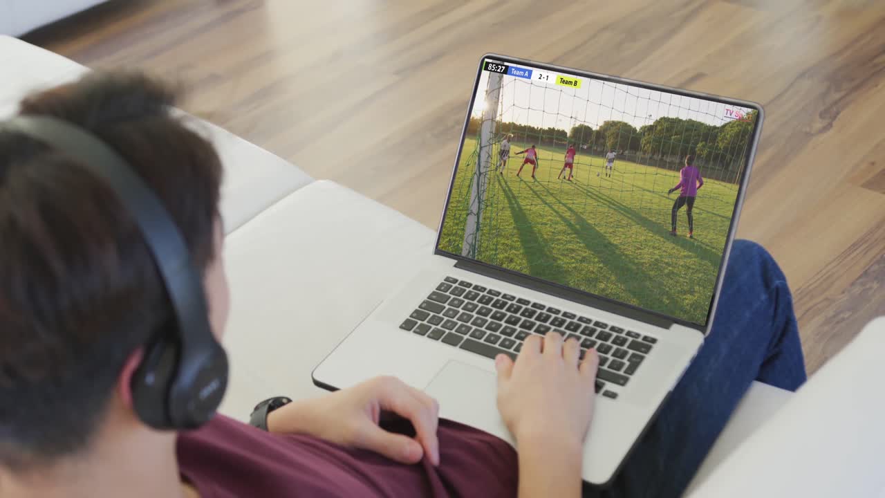 adolescente caucásico usando una computadora portátil con varios jugadores de fútbol masculino jugando un partido en la pantalla