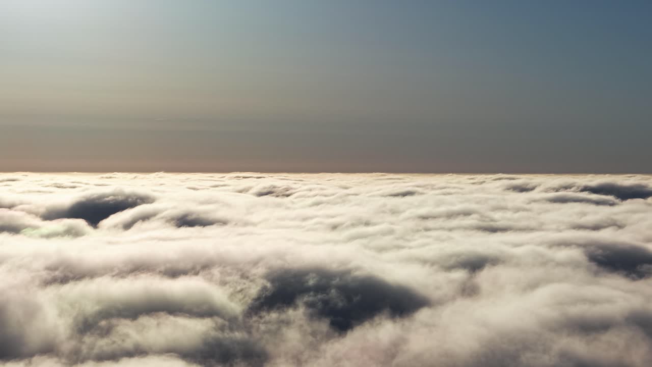 Golden light over dense cloudscape extending toward distant horizon