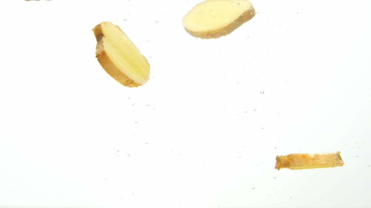 trozos de jengibre fresco ahogándose con burbujas de agua aislado sobre fondo blanco.