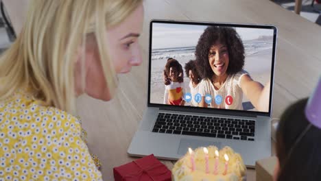 Caucasian-mother-and-daughter-sitting-at-table-using-laptop-having-birthday-video-call