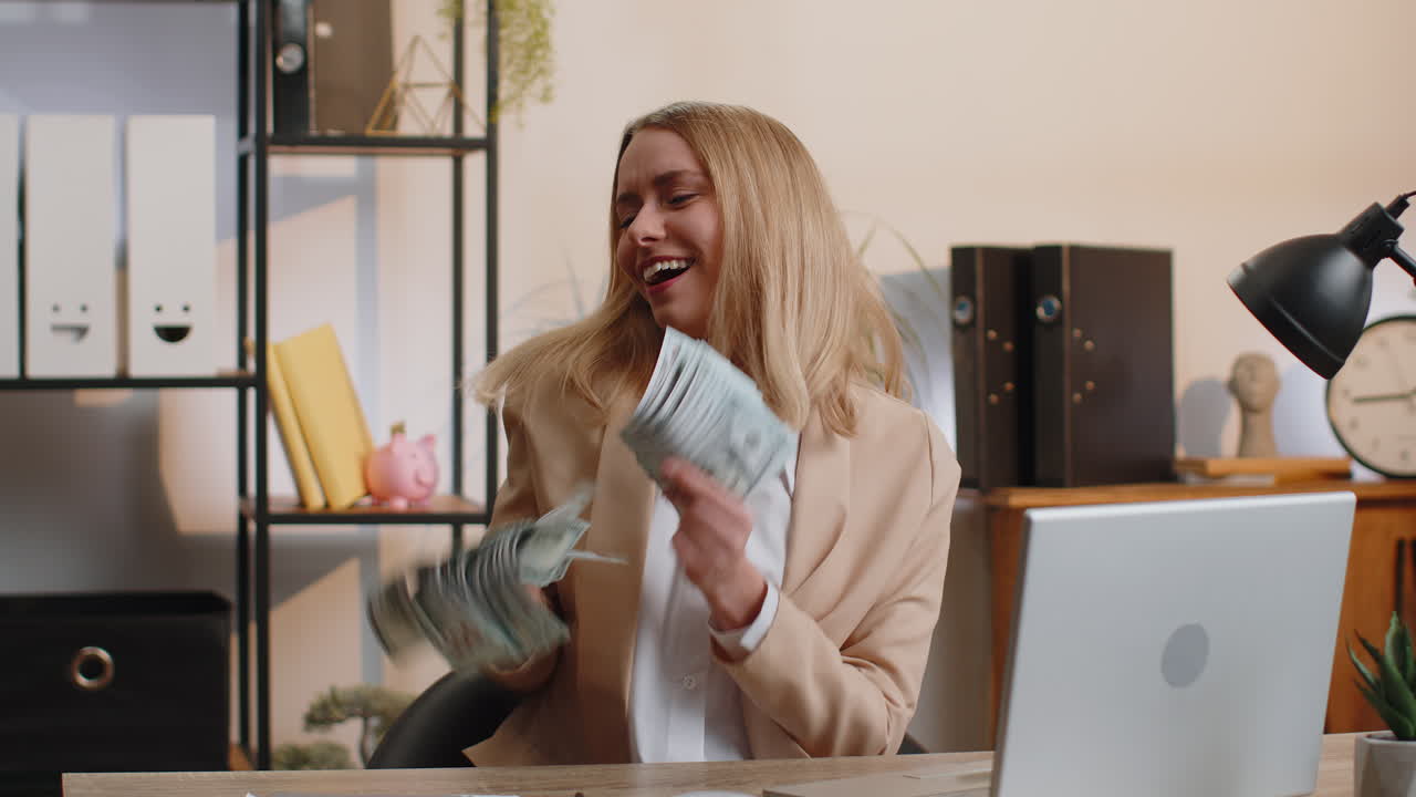 Jonge zakenvrouw winnares met een waaier dollarbiljetten viert dansend succes, carrière en salaris.