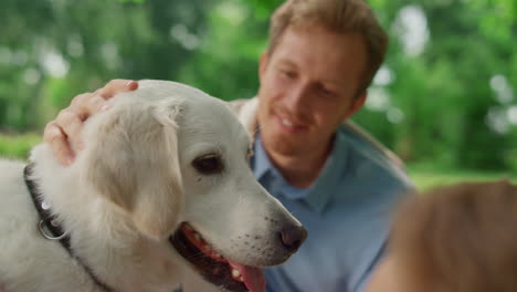 Happy-dog-enjoy-caressing-on-picnic-close-up.-Smiling-man-fondle-white-pet.