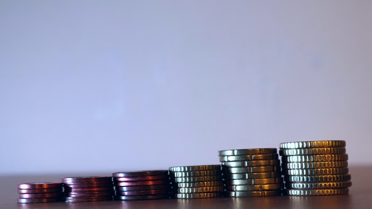 primer plano de las manos manteniendo cada una de las monedas del montón de monedas o dinero dispuestas en línea creciente, concepto de ahorro de monedas extranjeras