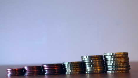 Close-up-shot-of-the-hands-keeping-each-of-one-coin-from-the-pile-of-coins-or-money-arranged-in-growing-line,-Foreign-coins-saving-concept