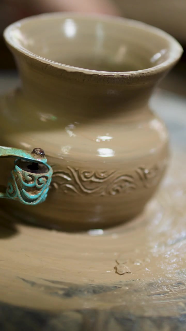 Primo piano di un artigiano che incide disegni tradizionali su un vaso di ceramica bagnato in Thailandia