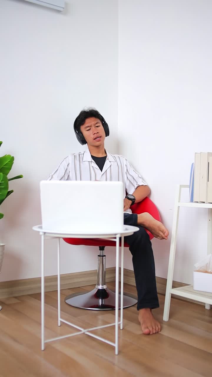 Young man enjoying coffee break while listening to music on laptop