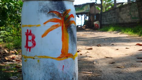 full shot, a white drum with a red bitcoin logo and orange tree drawing on the bitcoin beach in el salvador, mexico, another with drum with a bitcoin logo in the background