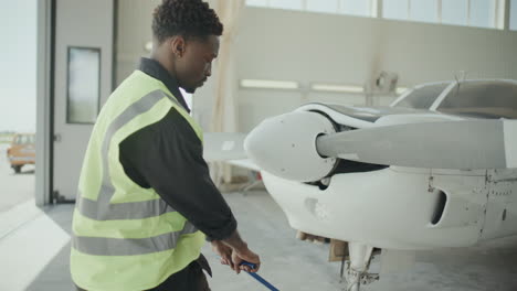 ground crew member pulling airplane through aviation hangar