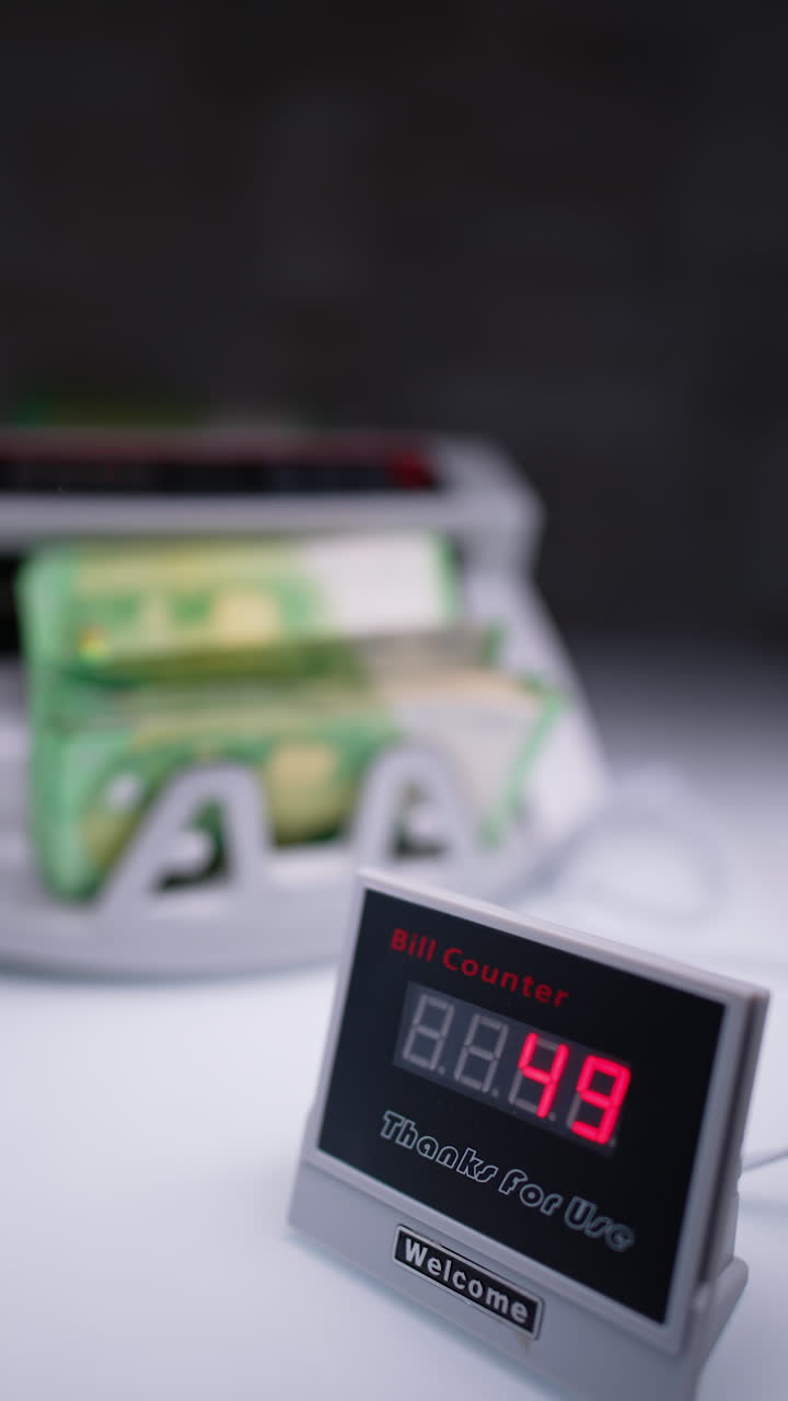 Display showing the quantity of banknotes in cash counting machine. Device counts money at blurred backdrop. Vertical video.