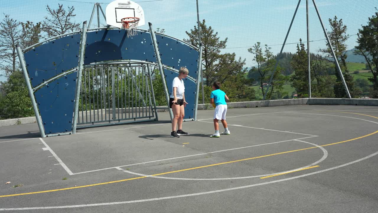 Donna e ragazzo giocano a basket in un campo all'aperto