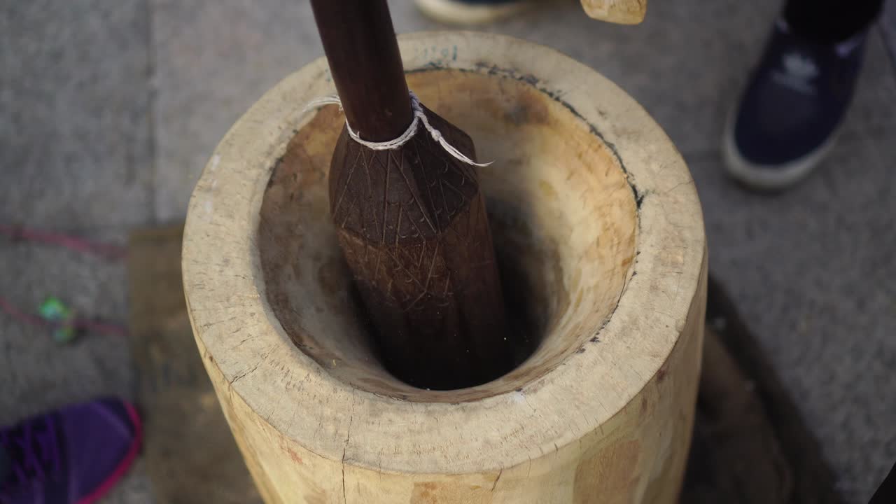 The process of making traditional Thai desserts using large wooden mortars.