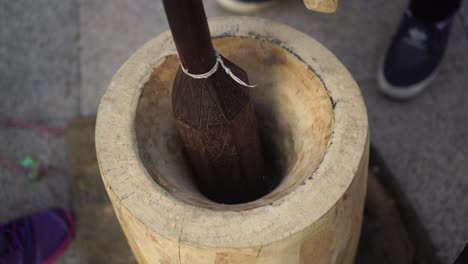 the process of making traditional thai desserts using large wooden mortars.