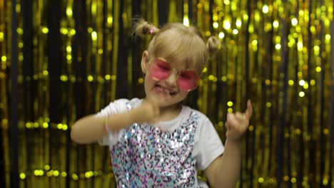 Child-dancing-waving-hands-fooling-around.-Girl-4-5-years-old-posing-on-background-with-foil-curtain