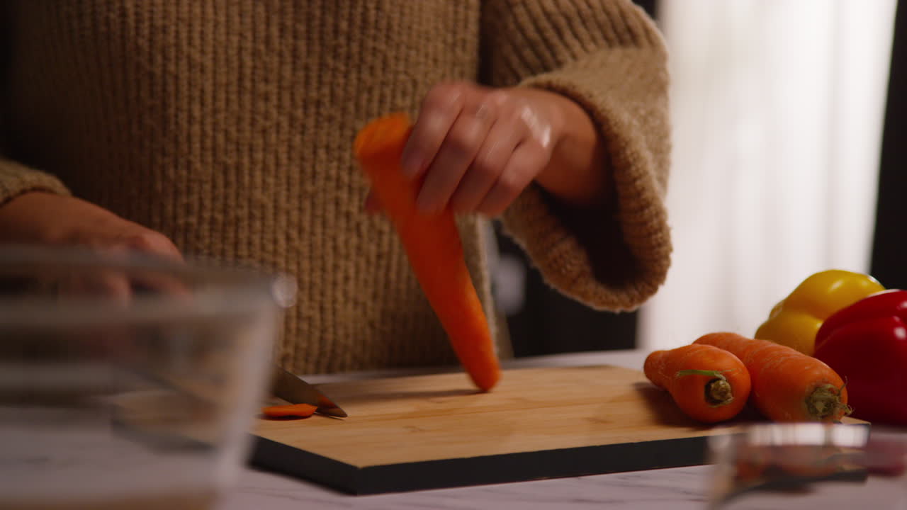 primer plano de una mujer en casa en la cocina preparando verduras frescas saludables para una comida vegetariana o vegana cortando zanahorias a bordo 3