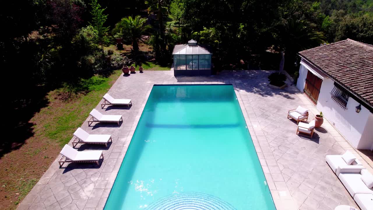 Droneoptagelse fra højde afslører luksusvilla med pool, veranda og tropisk have.