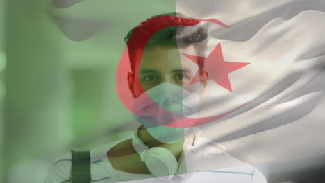 animation of flag of algeria waving over man wearing face mask during covid 19 pandemic