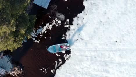 Top-View-Of-Man-In-Boat-Breaking-Ice-Using-Shovel-In-Winter