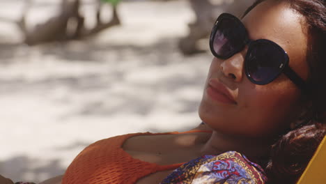 close up of latin girls contented face with sunglasses chilling in shade on beach