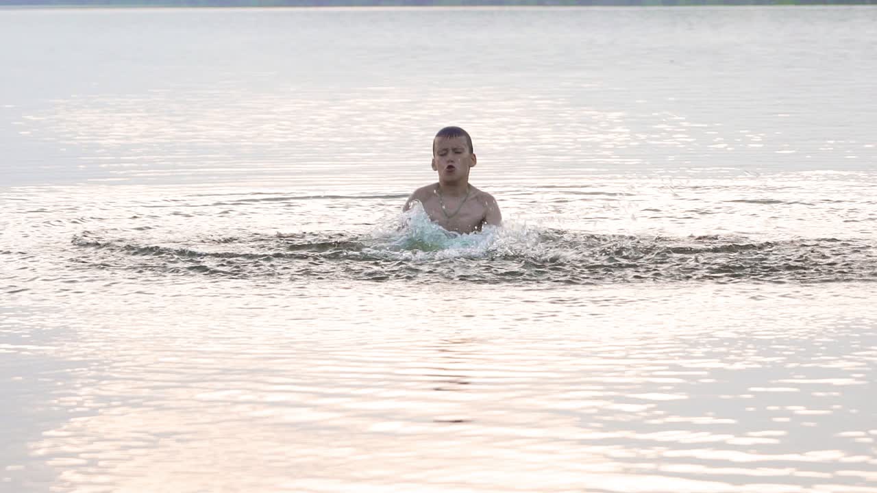 The boy is bathed in the river and splashing water. Slow motion shooting.