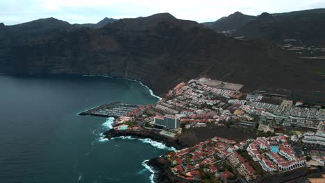 aerial dolly away from grande mountains coastal village in tenerife spain, establishing shot