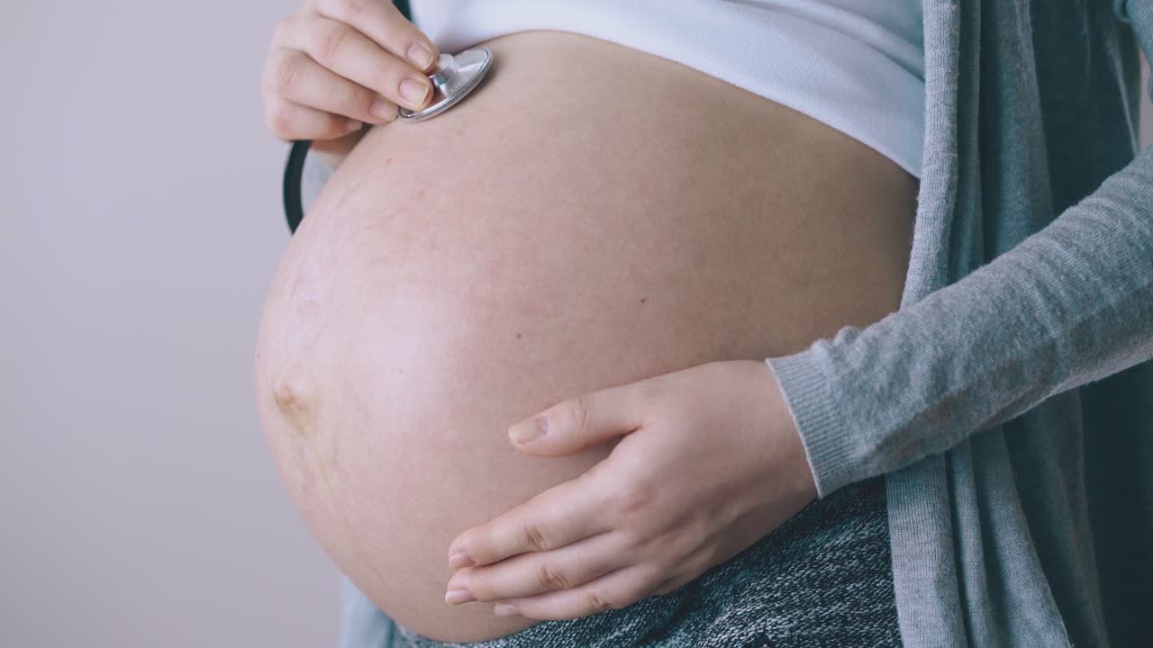 una donna incinta ascolta il battito cardiaco del bambino con uno stetoscopio