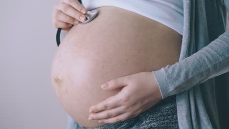 una mujer embarazada escucha los latidos del corazón de su bebé con un estetoscopio