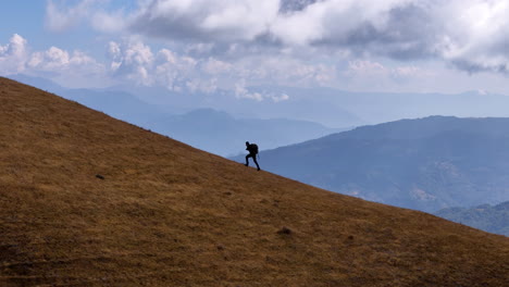 Ein-Männlicher-Tourist,-Der-Auf-Den-Hügeln-Des-Peaky-Peak-In-Nepal-Läuft,-Landschaftsaufnahme-Mit-Drohne,-4K