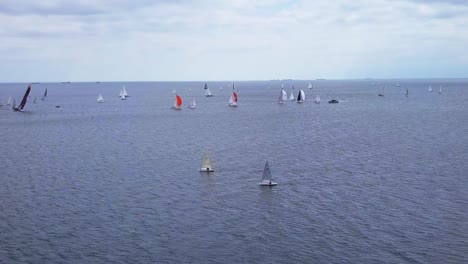 Aerial-View-Of-Sailboat-Regatta-In-A-Sea-Under-A-Cloudy-Sky