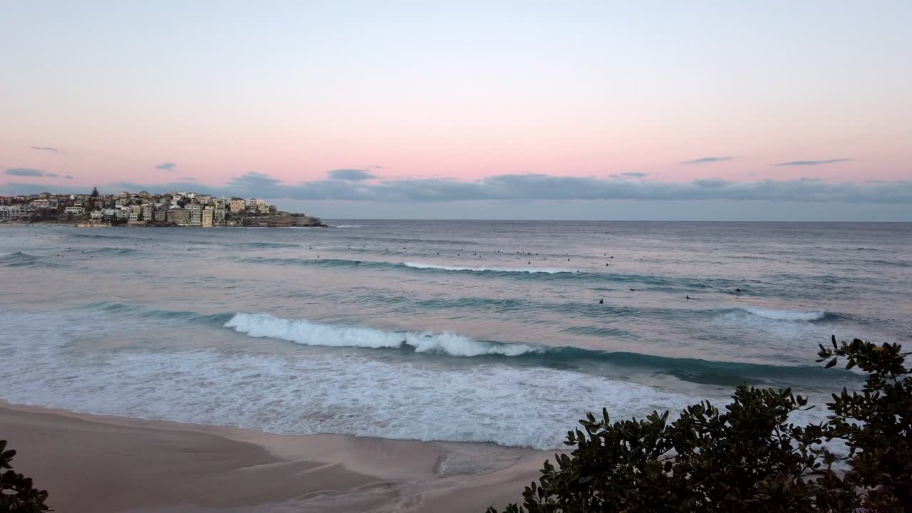 rompiendo olas en la costa con surfistas en bondi beach al atardecer en sydney, nsw, australia