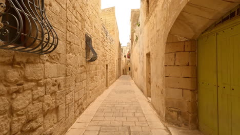 pov shot while walking through narrow alley of mdina, the old capital of the state of malta at daytime