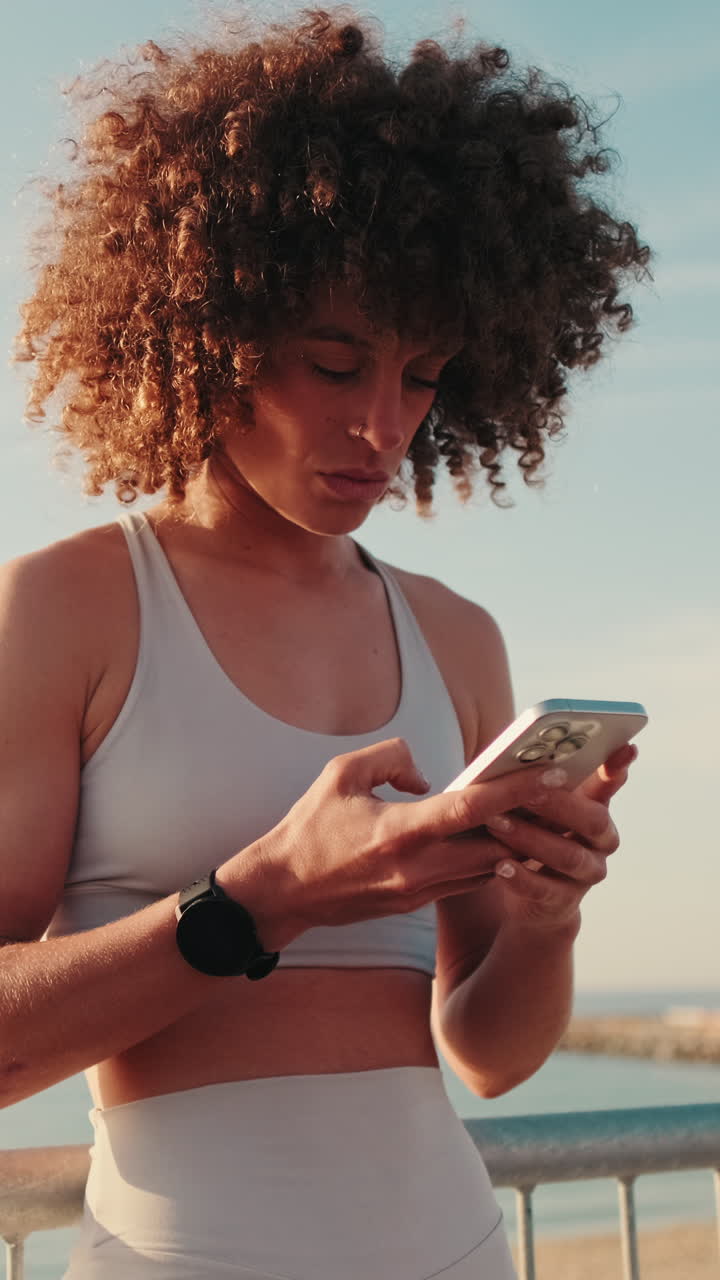 Sporty Woman Checks Phone at Beach