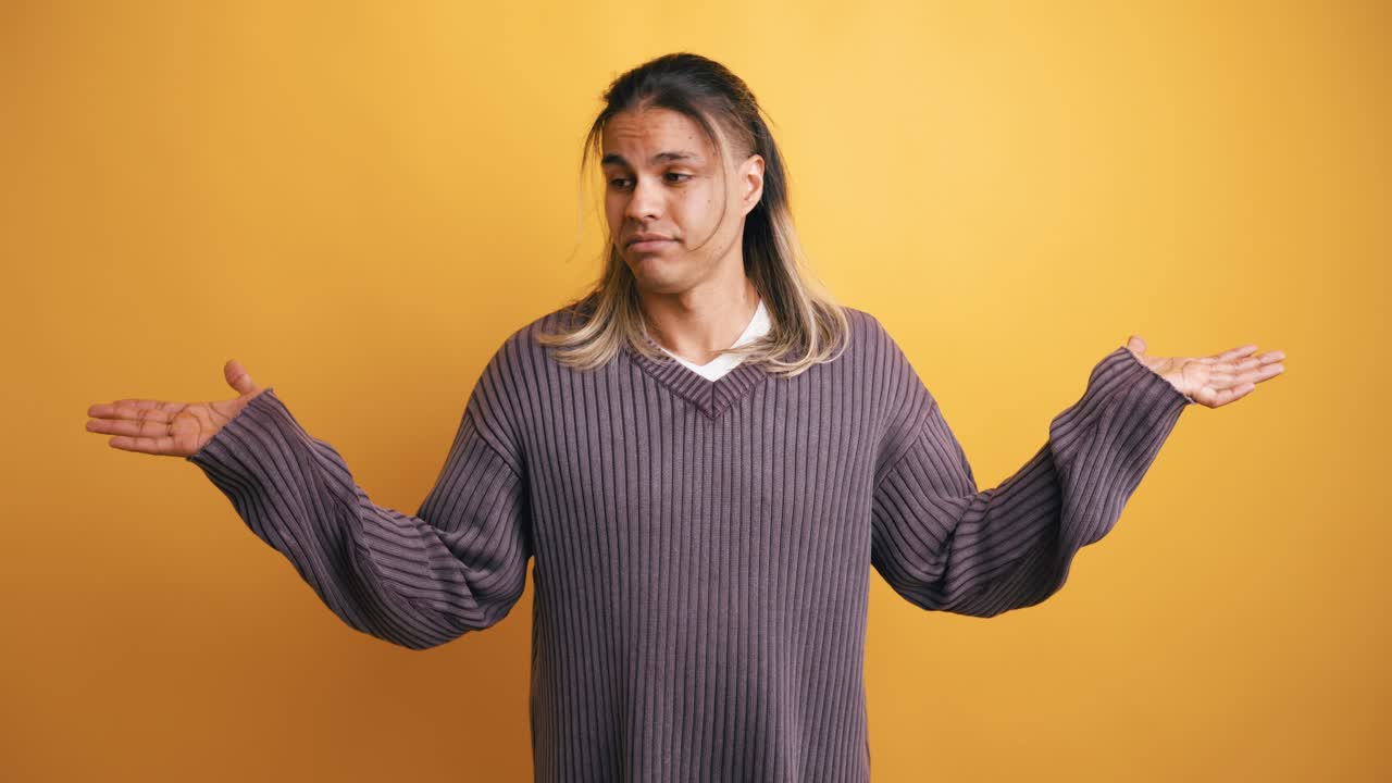 Young Man Shrugging and Smiling on Yellow Background