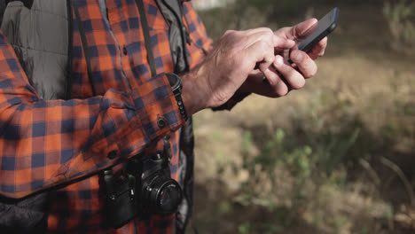 close up view of senior man holding smartphone in forest