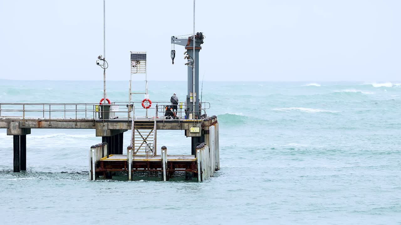 A serene view of a pier at Port Campbell, Australia, with gentle ocean waves and overcast skies captured in a 21-second video