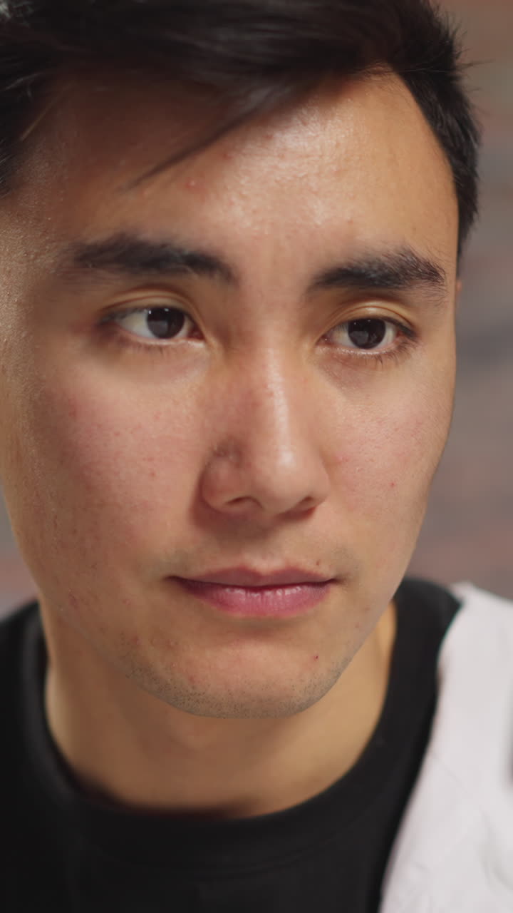 Tired Asian man doctor internist in white robe looks at plastic tube with patient blood sample working in hospital laboratory extreme closeup